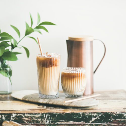Caffè freddo in bicchieri con latte e cannucce a bordo su un tavolo in legno rustico